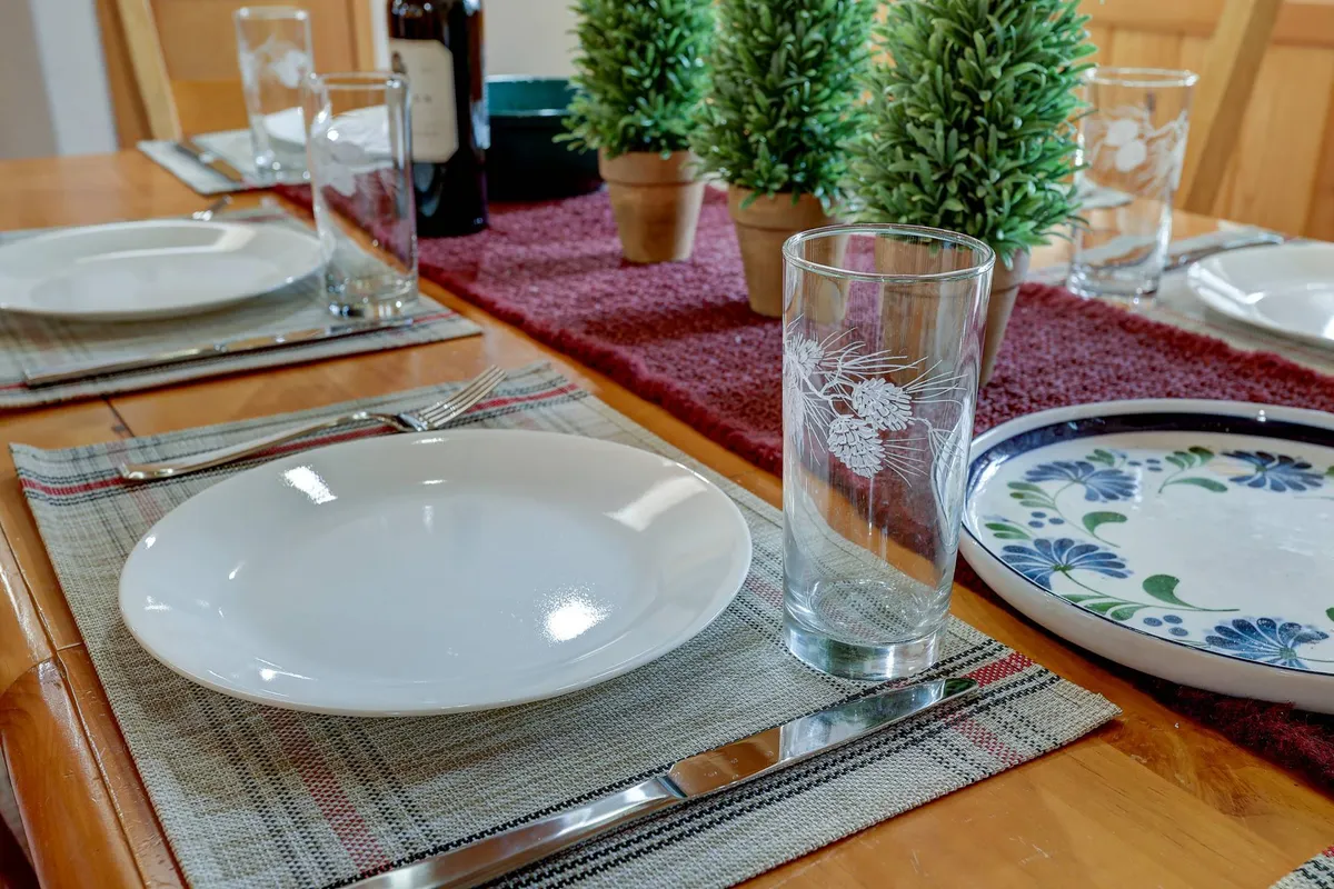 A welcoming dining table with thoughtful place settings, small potted plants, and a decorative wine bottle, creating an atmosphere perfect for celebrating and sharing stories after a day spent outdoors.